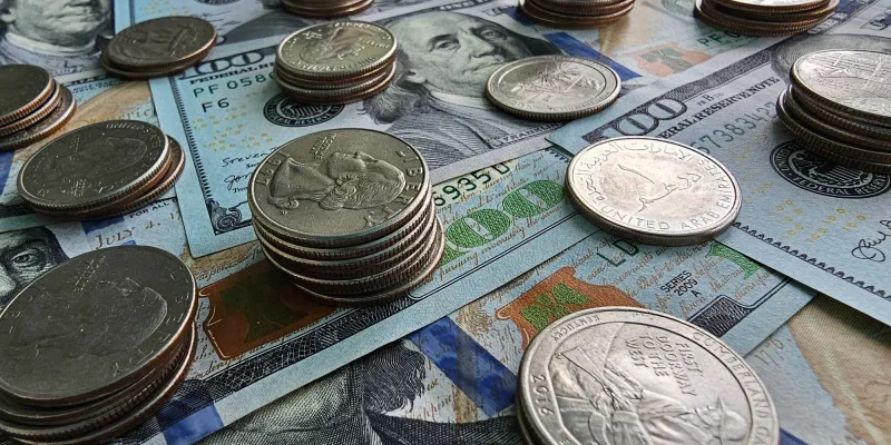 Various coins scattered on US bills and a passport.