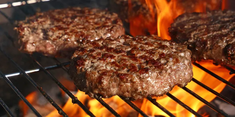 Close up beef or pork meat barbecue burgers for hamburger prepared grilled on bbq fire flame grill, high angle view