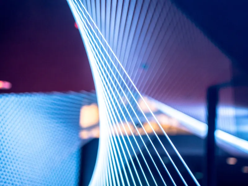 Multiple glowing blue and white fiber optic cables against a dark background.