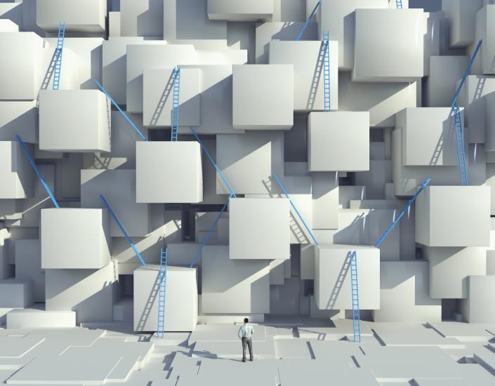 Caucasian man looking at blue ladders on cube wall Caucasian man looking at blue ladders on cube wall