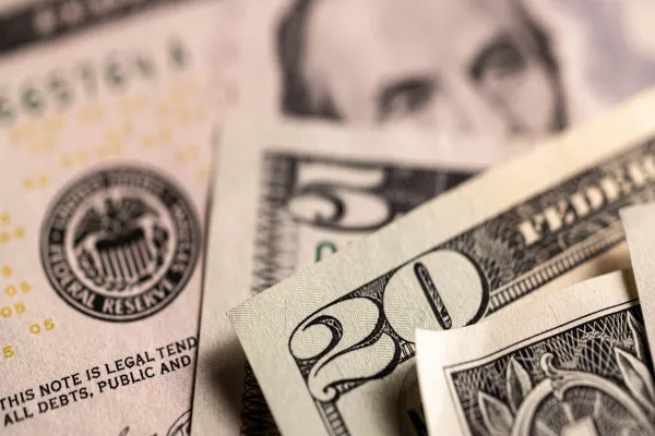 Several U.S. dollar bills, including a fifty and a twenty, arranged on a surface.