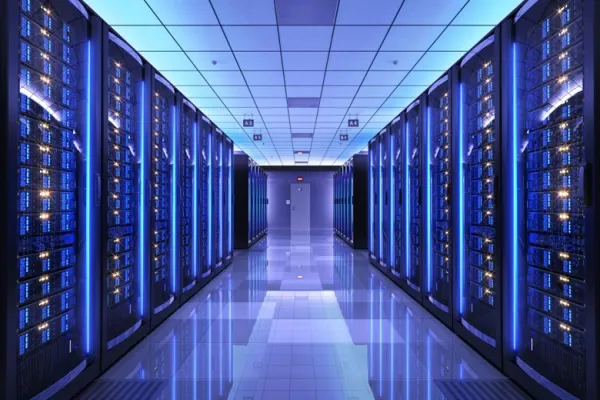 Server racks filled with blue-lit computer hardware in a data center hallway.